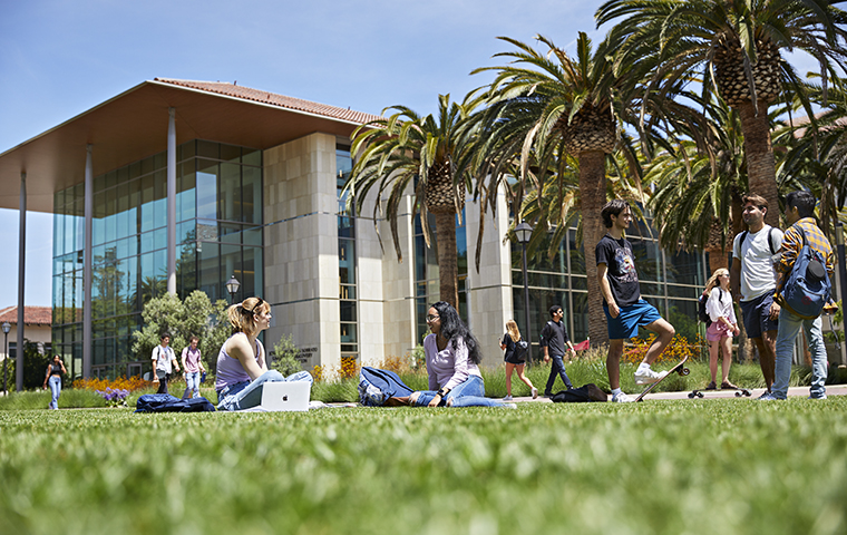Students seated on lawn in front of Sobrato Campus building