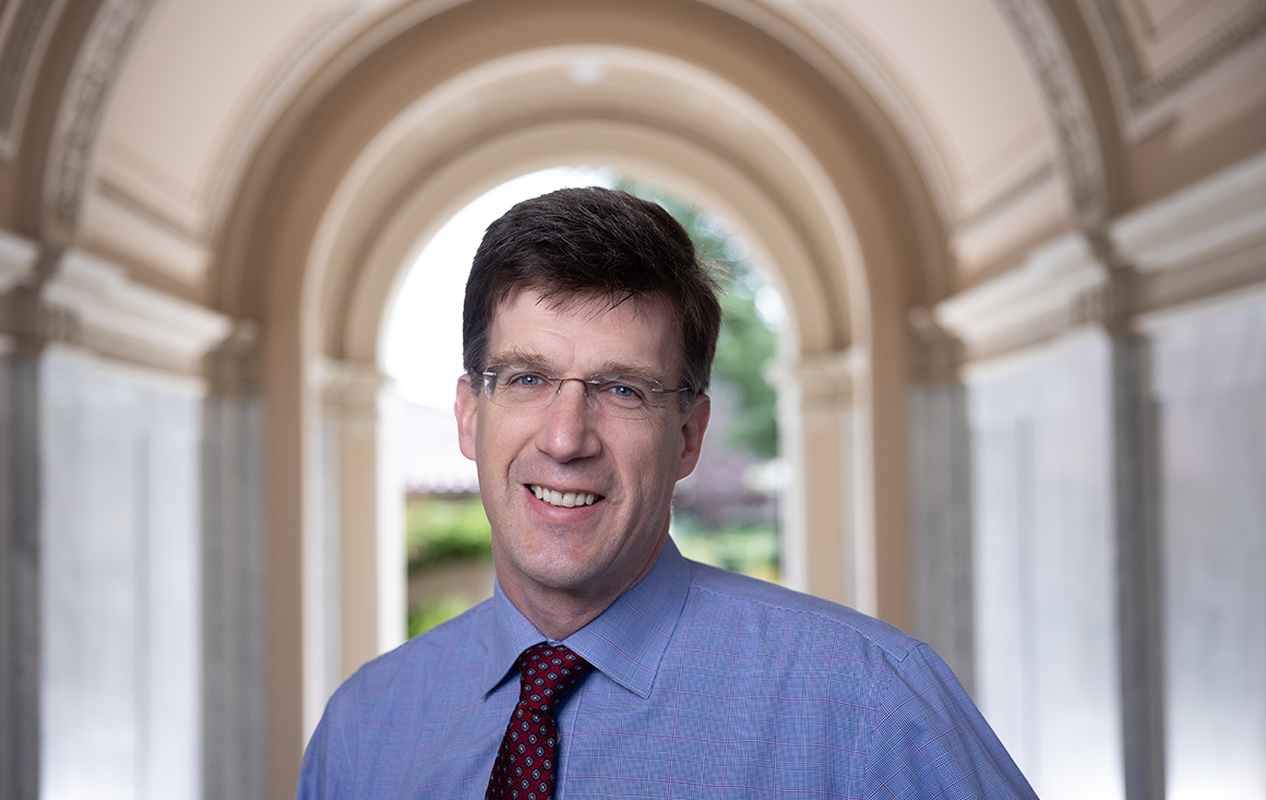 A professor stands with his head framed by the O'Connor Hall archway.