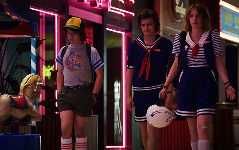 Three characters from Stranger Things walk through the mall