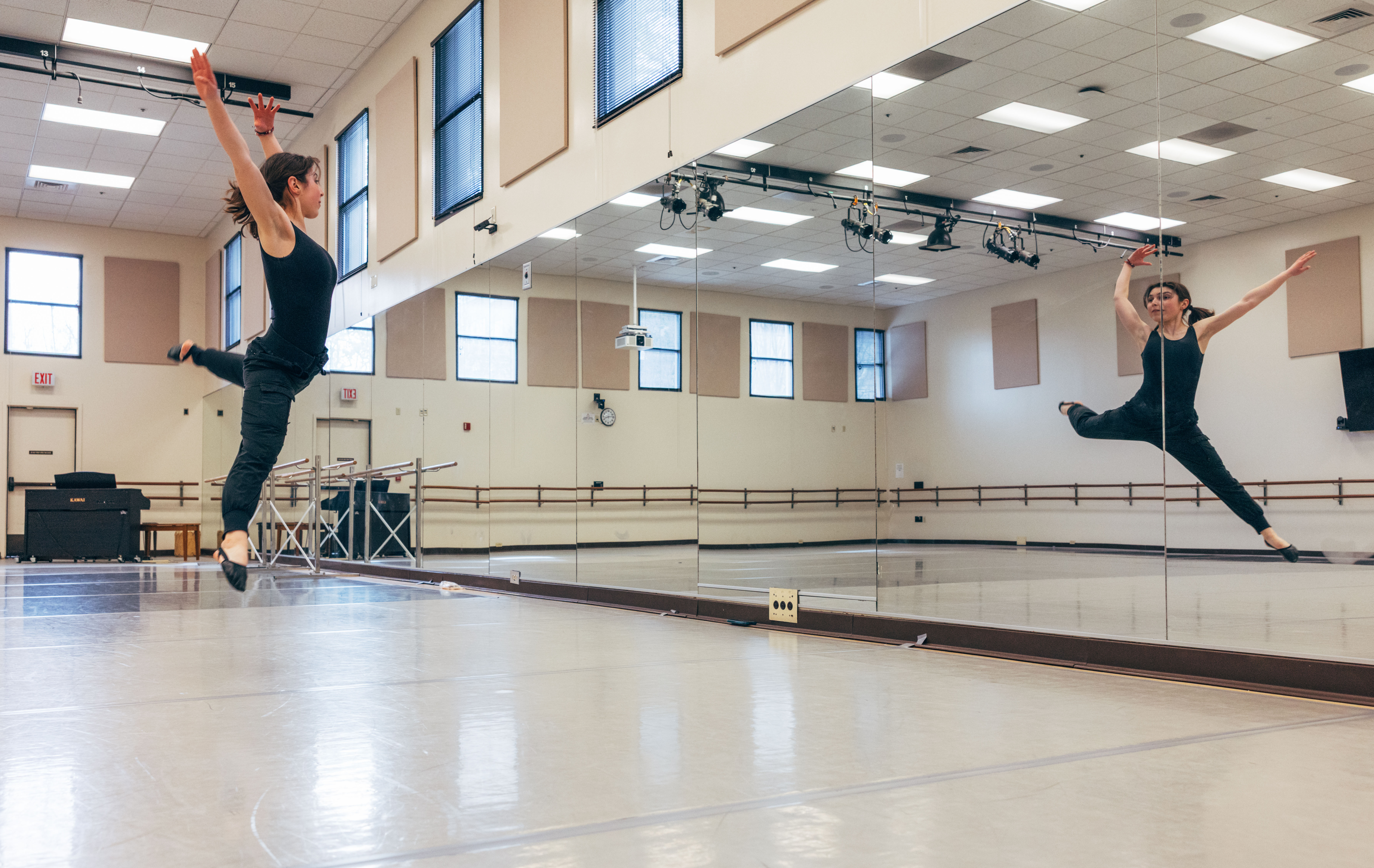 Dancer leaps through air in dance studio.