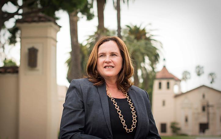 A person standing outdoors in front of palm trees and buildings. image link to story