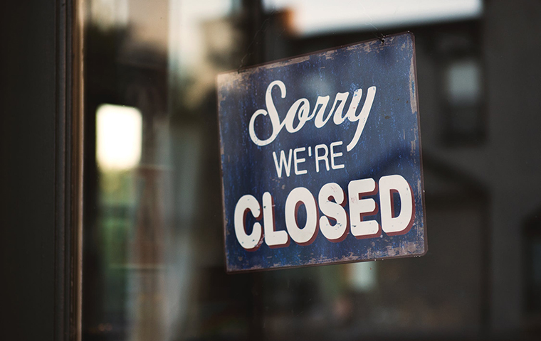 A closed sign on a glass door storefront image link to story