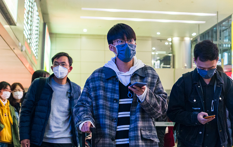 A man walks through an airport with a mask on