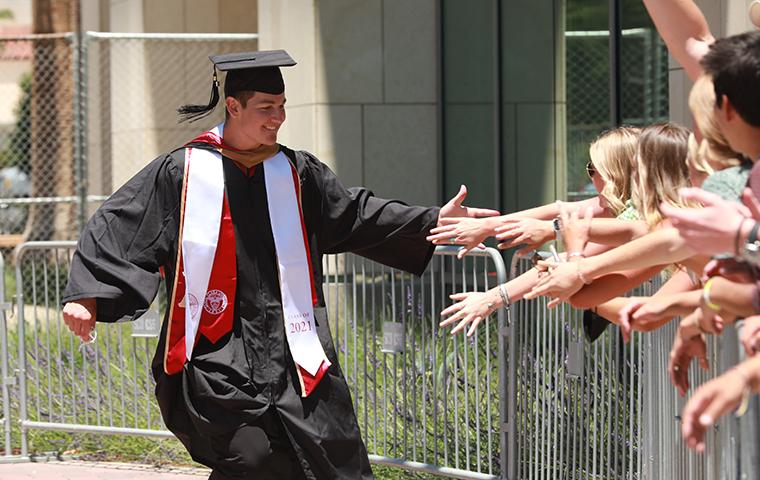 Graduating student high fives line of people