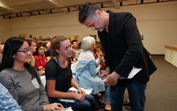Khaled Hosseini signs a copy of a book as a student looks on.