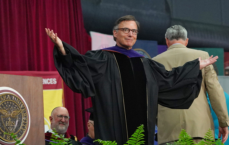 SCU President Kevin O'Brien on stage at his presidential inauguration, hands out to his side