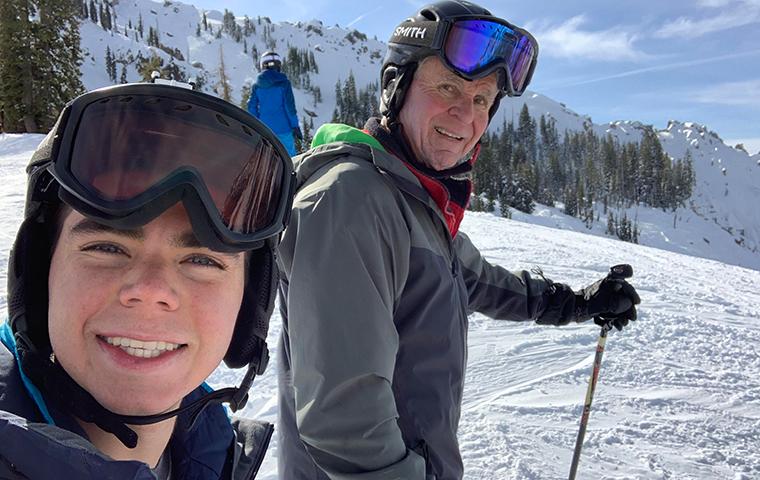 Max Campos and his grandfather skiing on the top of a mountain