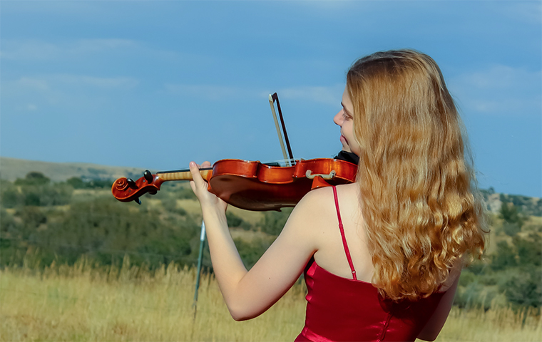 Natalie Plaia plays a violin in a field
