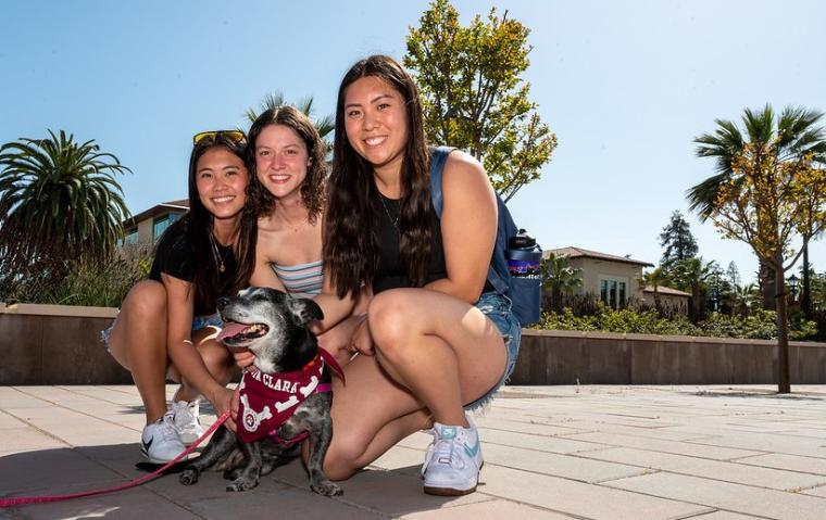 Three students pose with dog during Day of Giving 2022