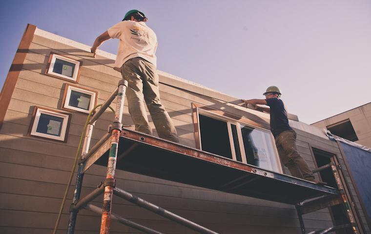 Two people working on a tiny house under clear skies. image link to story