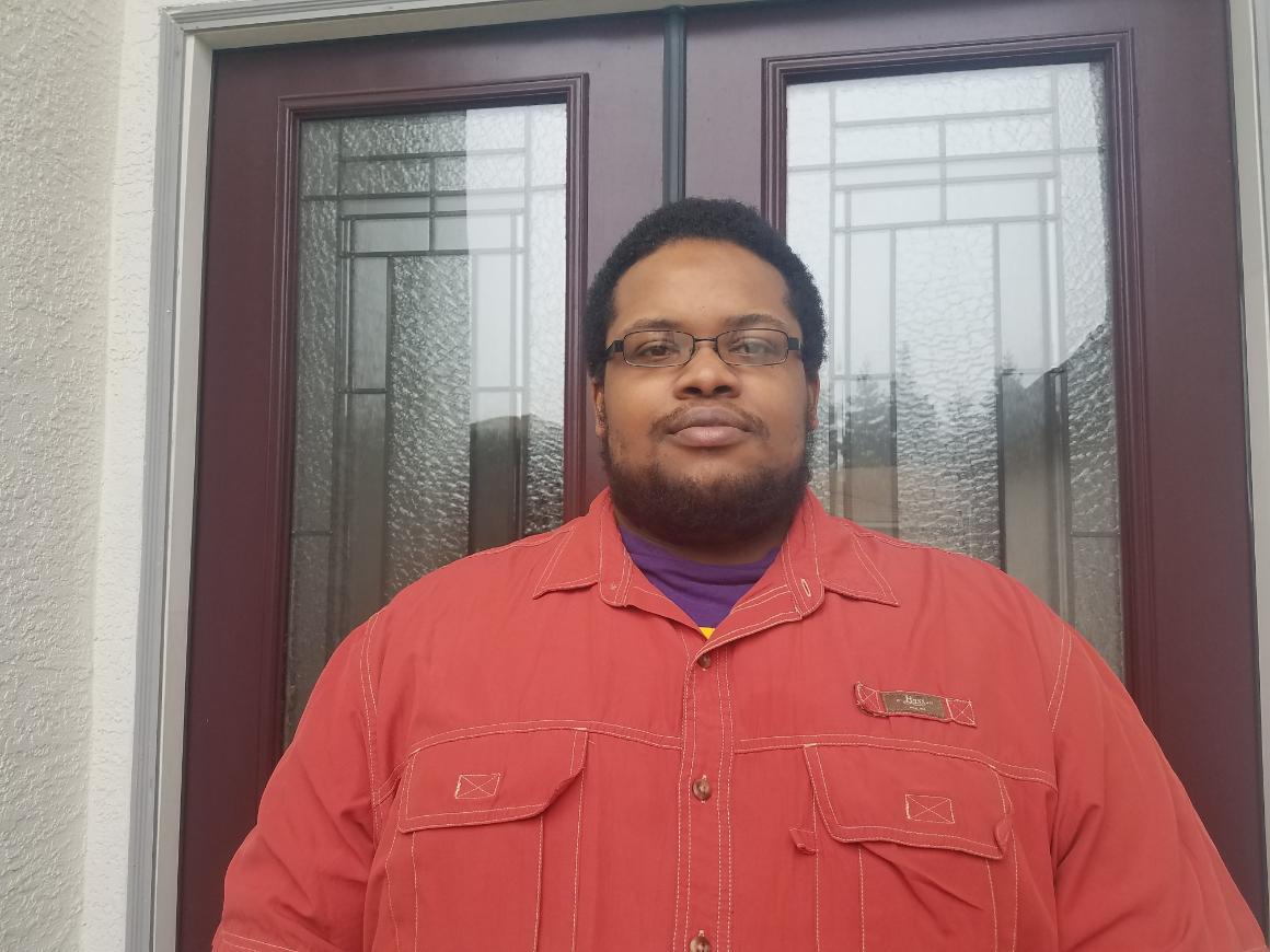 A person in a red shirt in front of glass doors.