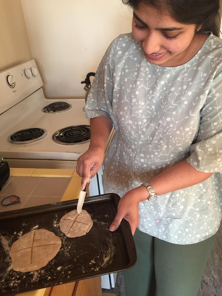 Student cutting freshly made communion bread with knife.