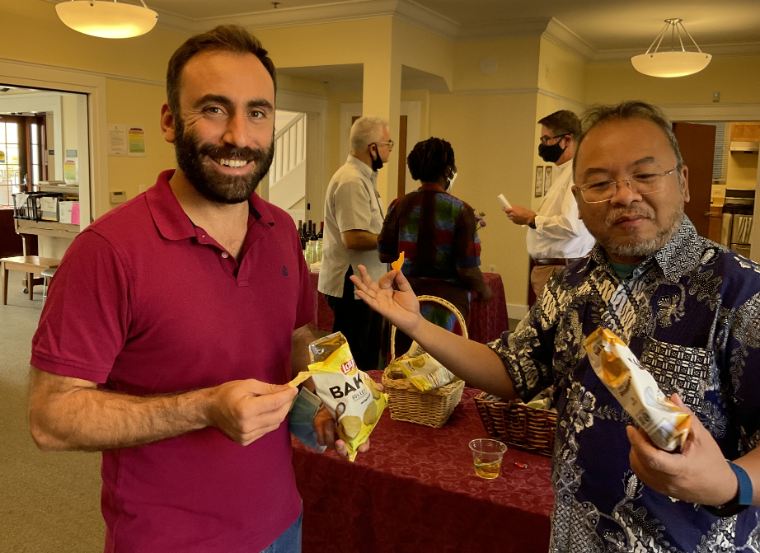 Two people holding snacks and smiling at 'Fall Orientation 2021' event.