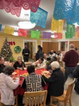 People gathered in a decorated room with colorful banners and a Christmas tree.