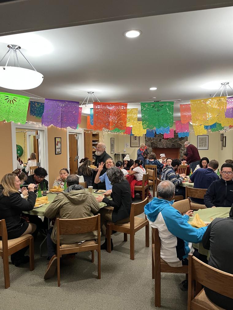 People gathered in a room decorated with colorful papel picado banners.