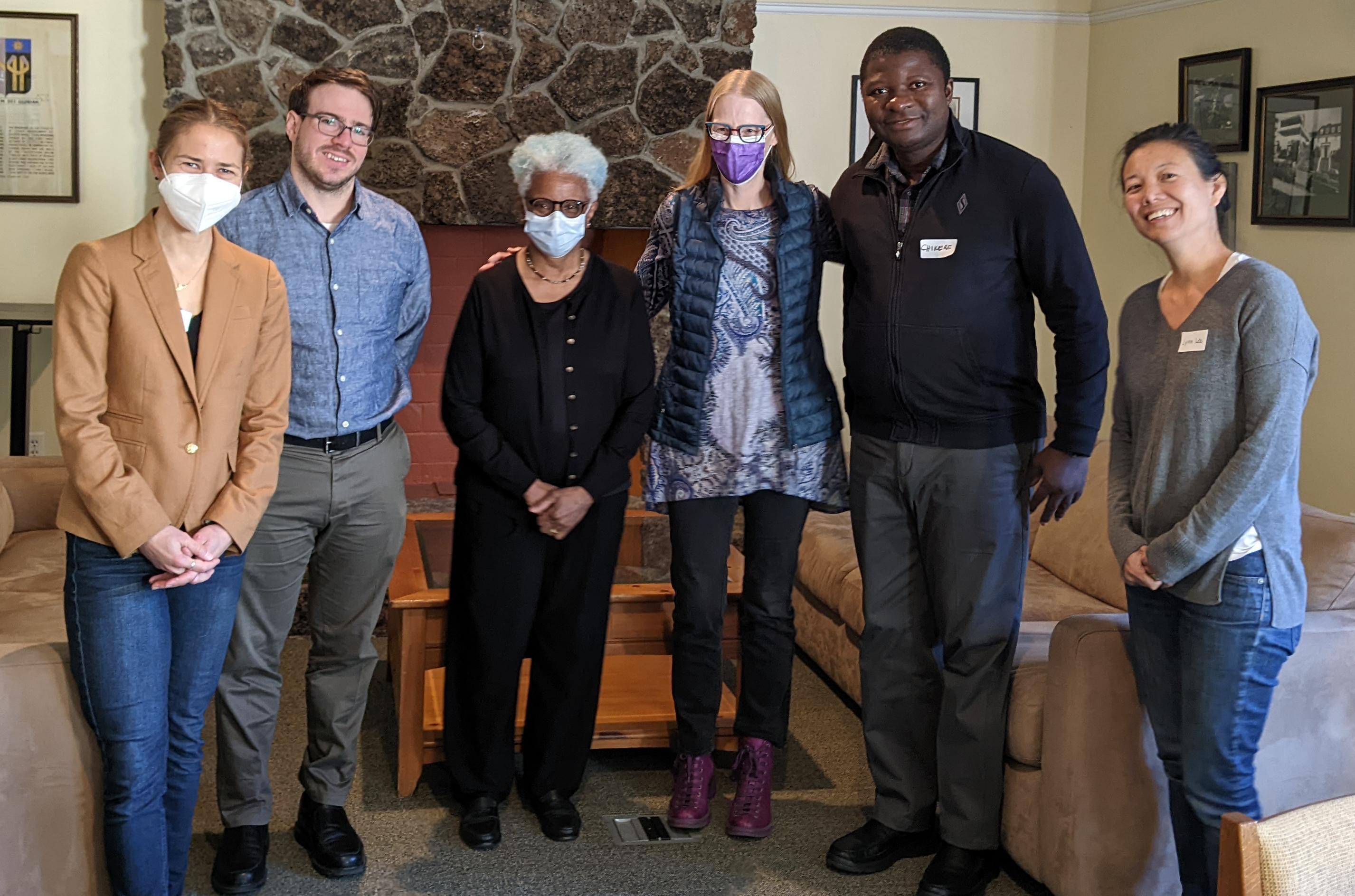 A group of six people standing in a living room.