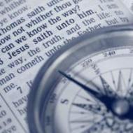 A compass laying on a book with text.