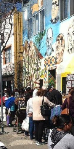 A crowded street scene in Oakland with a mural in the background.