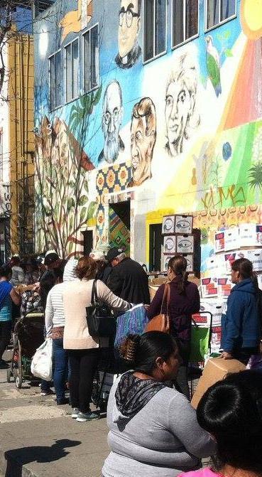 A crowded street scene in Oakland with a mural in the background.