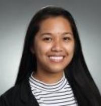 A person smiling against a gradient gray background.