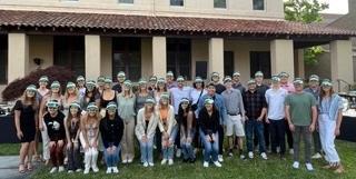A group of people standing outside a building with the text 