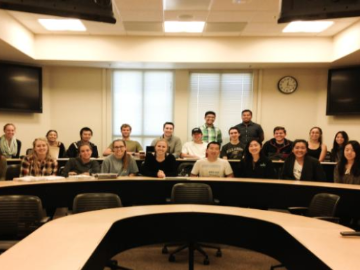 Classroom with seated students and instructors posing for a group photo.