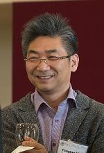 A person wearing glasses holding a wine glass and a book.