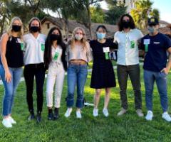 A group of seven people posing outdoors with trees in the background.