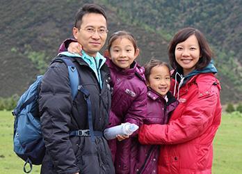 A family of four smiling outdoors in winter clothing.