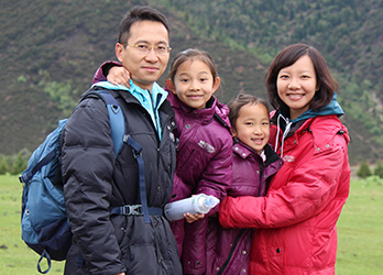 A family of four smiling outdoors in winter clothing.