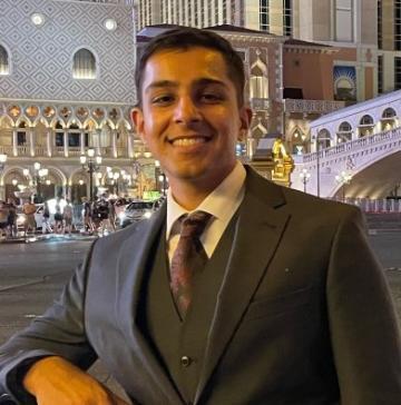 A person in formal attire with city lights in the background.