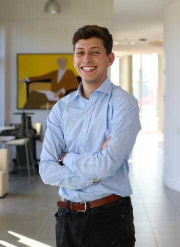 A person in a blue shirt standing with arms crossed indoors.