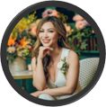 Minnie Uyen Thai smiling seated in chair with her hand on her chin