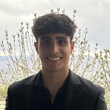 Man in black suit smiling outdoors