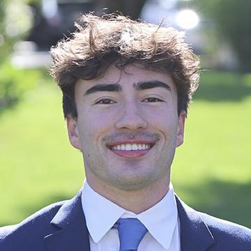 Man in suit and tie outdoors smiling