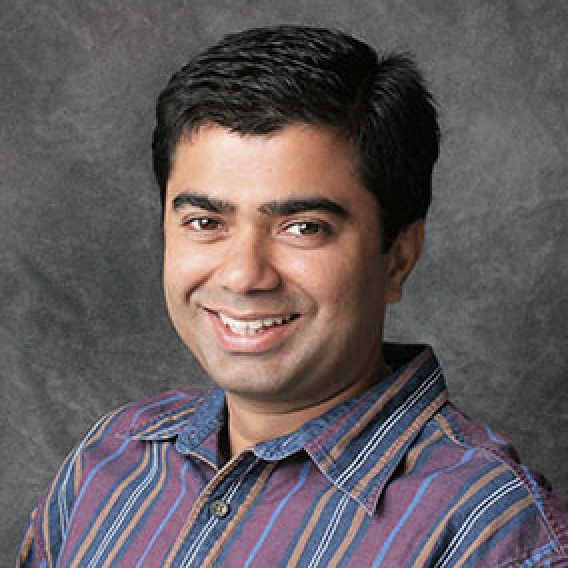 A person smiling with a gray background.