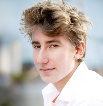 A person in a white shirt with blurred cityscape background.