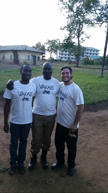 Three men wearing matching white shirts standing outdoors.