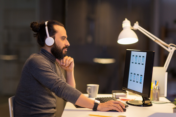 Picture of a man wearing headphones and looking at a laptop
