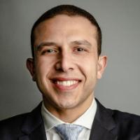 A person in a suit smiling with arms folded.