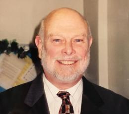 Man smiling in a suit and tie.