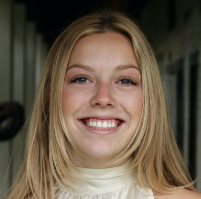 A person smiling while standing in a hallway.