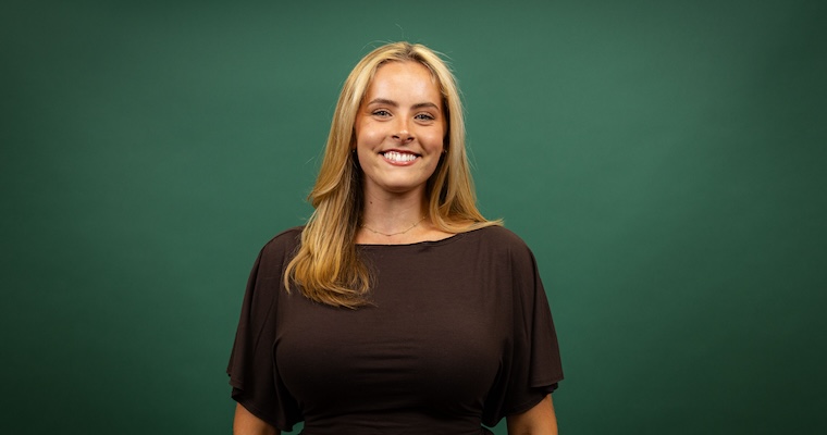 Young woman smiles in front of green backdrop.