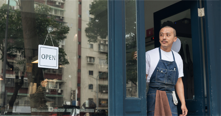 Business owner stands outside of his shop. 