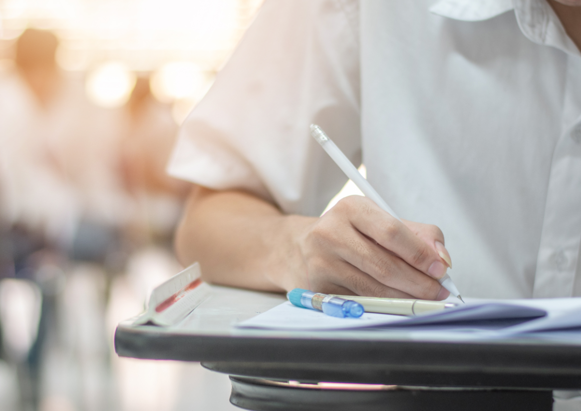 Applicant writing on paper with extra pens nearby