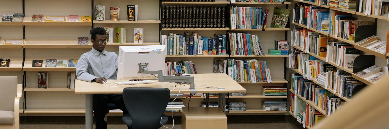 A serene library setting with a man studying and bookshelves filled with diverse literature