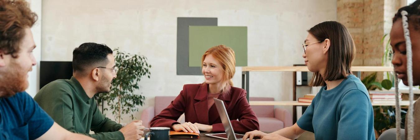 Five professionals engaged in a meeting around a conference table