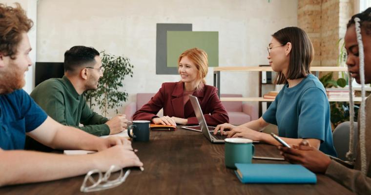 Five professionals engaged in a meeting around a conference table