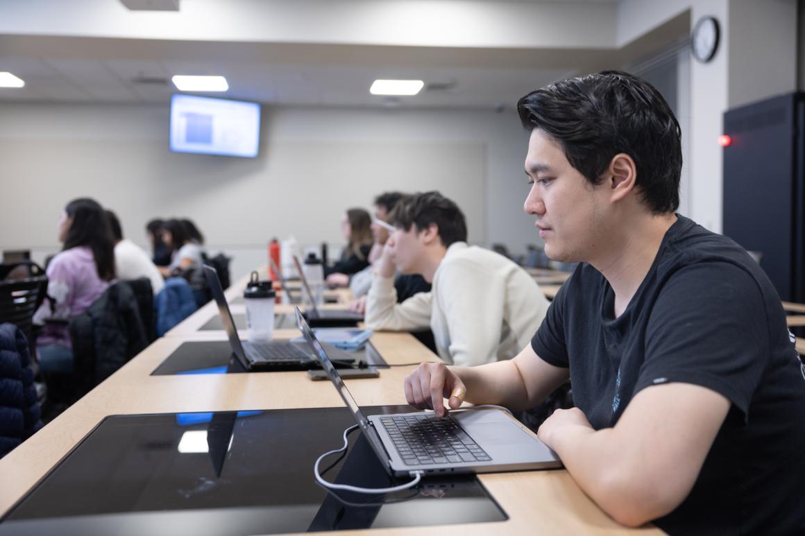 Leavey School of Business graduate students looking at laptops during class