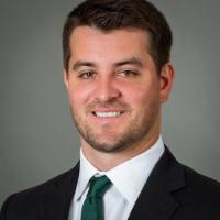 A person in a suit and tie smiling in a portrait.